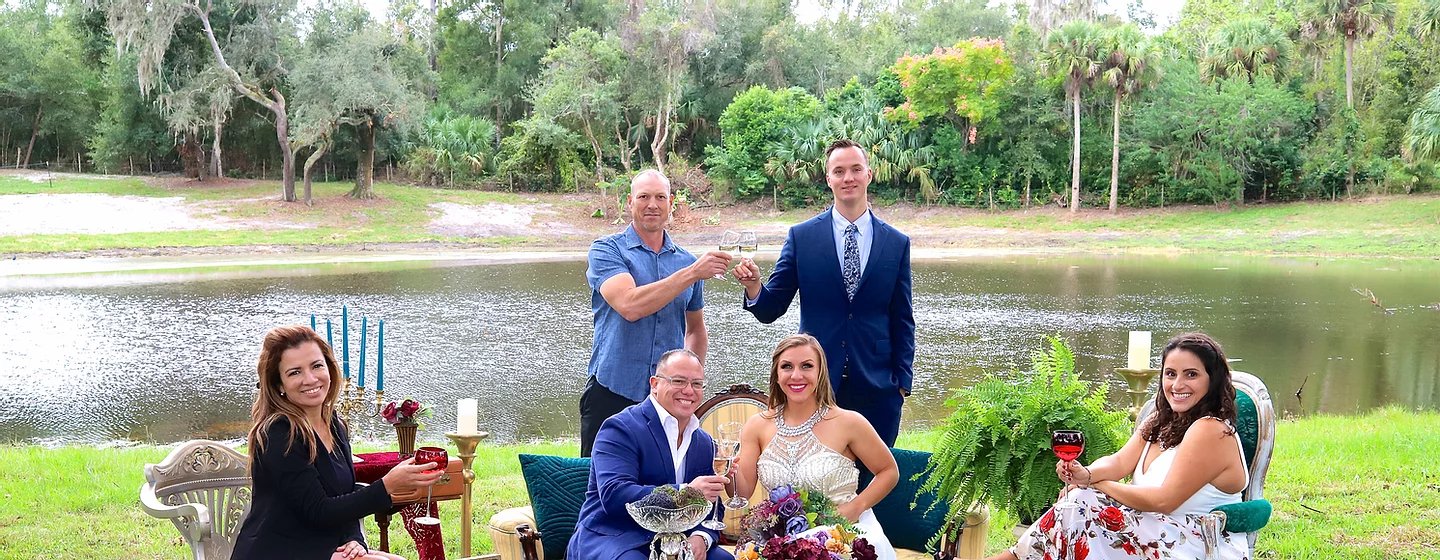 Family and friends toasting at a gathering on the hilltop lawn, the property's pond and tree line behind them